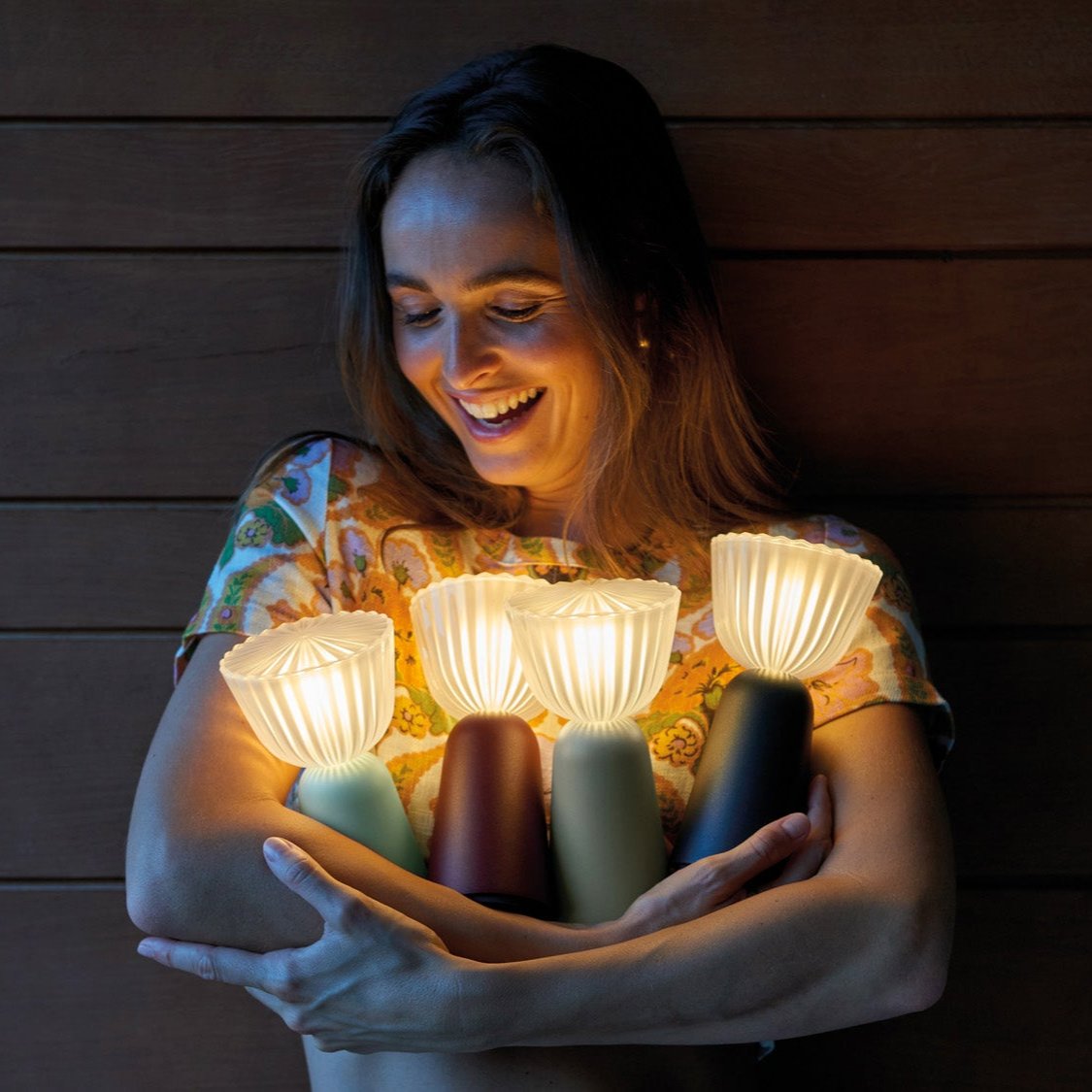 A woman holding 4 Fermob Swiing lamps